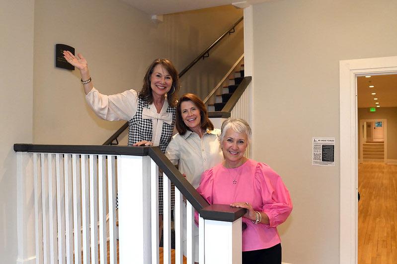 Converse alumnae stand on the refurbished stairs inside Cudd hall smiling.